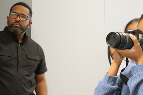 Docente junto a estudiante que utiliza una cámara. 